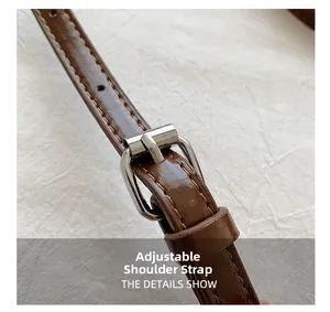Close-up of adjustable brown leather shoulder strap with silver buckle and yellow stitching