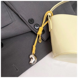 Détail d'un cordon jaune et d'un pendentif coeur argenté sur un sac seau chic