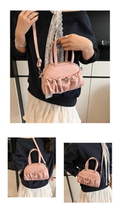 Detail of light pink pleated handbag featuring silver metal clasp and crossbody strap