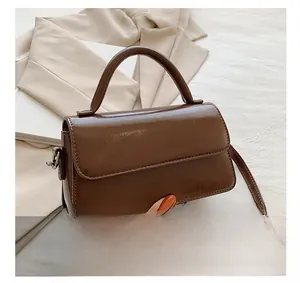 Close-up of a dark brown glossy leather crossbody bag featuring a minimalist top handle