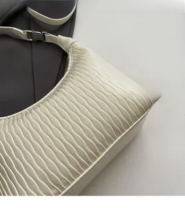 Detailed close-up of soft pleated texture on a cream-white crossbody dumpling bag