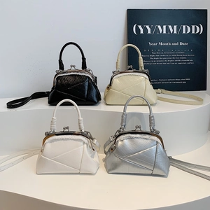 Detail view of four vintage kiss-lock handbags in black, cream, white, and silver leather