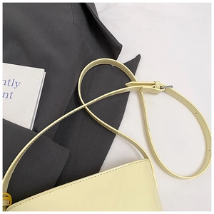 Gros plan du sac seau en cuir jaune crème avec bandoulière à boucle argentée réglable