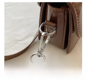 Close-up of silver metal hardware and fine stitching on dark brown leather handbag