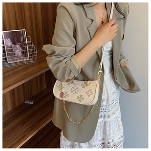 Detail of clover print handbag featuring gold chain and ivory white faux leather material