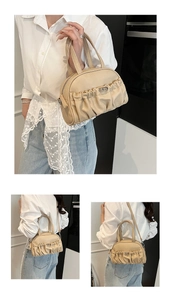 Detailed view of beige pleated handbag showing leather texture and metallic buckle accents
