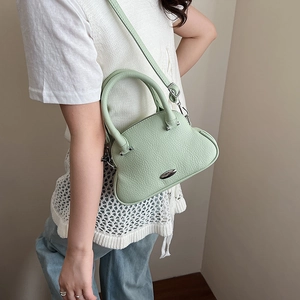 Dettaglio della borsa a mano verde menta in pelle martellata indossata a tracolla