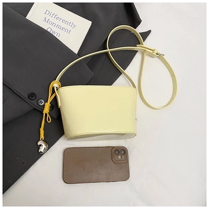 Sac seau jaune pâle en cuir texturé montré avec un téléphone portable pour la taille
