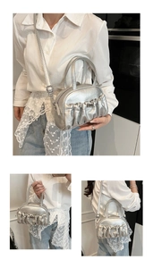 Detail view of silver metallic pleated bag showing handle, crossbody strap, and texture