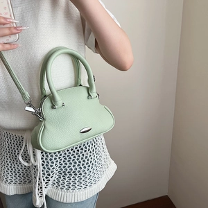 Modella che indossa una mini borsa verde chiaro in pelle con dettagli metallici argento