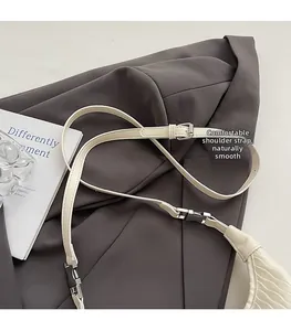 Detail of off-white leather shoulder strap with silver metal buckle and fine stitching