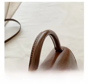 Detail shot of the reinforced brown leather handle and neat stitching on a vintage square bag