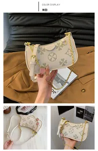 Detail of off-white shoulder bag featuring green clover print and strawberry charms