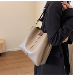 Detail of khaki bucket bag with Forever buckle on model in minimalist interior setting