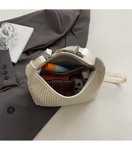 Detail view of the spacious inner compartment of this cream pleated crossbody bag