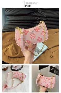 Detail view of pink underarm bag with litchi texture and golden chain strawberry charm