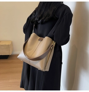 Detail of khaki leather bucket bag with brown wide strap and gold metal feet on bottom