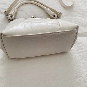 Detail view of white vintage kiss-lock handbag with crackle texture and metal clasp