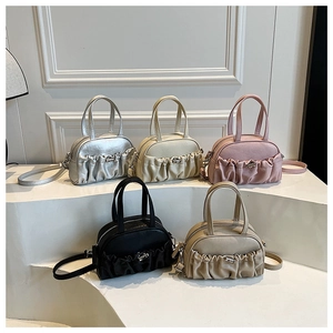 Multi-color pleated crossbody bowling bags displayed on a clean minimalist pedestal