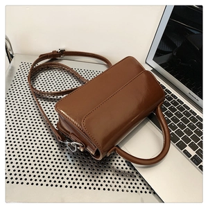 Detail of a brown leather crossbody bag featuring polished silver hardware and handle