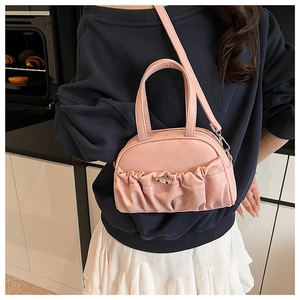 Detail of pink pleated handbag showing soft PU texture and silver metal twist lock