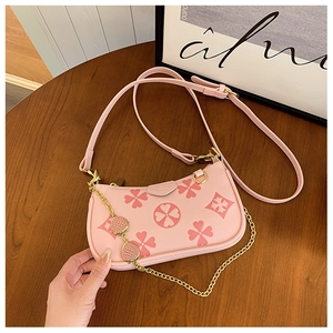 Detail of pink floral print handbag with strawberry charm chain and lychee leather texture