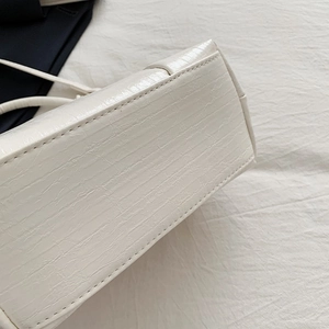 Close-up of crocodile pattern PU leather stitching and durable seam detail on white handbag