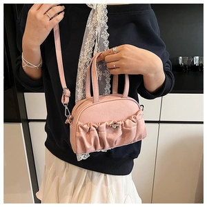 Detail view of pink pleated handbag showing the PU leather texture and metal buckle accents