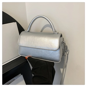Detail of silver metallic leather handbag with wrinkled texture and rounded handle