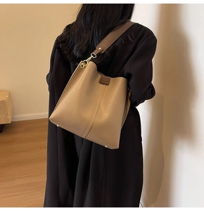 Detail of khaki leather bucket bag featuring wide shoulder strap and gold-tone hardware