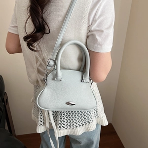 Dettaglio borsa in pelle azzurra con finiture argentate e design curvo moderno
