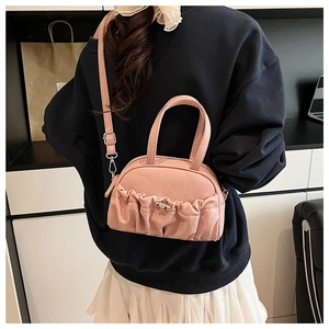 Detailed view of pink pleated leather handbag with metallic turn-lock buckle closure