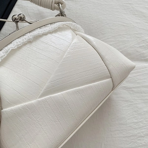 Close-up of vintage cream clasp bag featuring distressed leather texture and lace trim