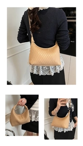 Detail of pleated beige shoulder bag showing vertical wavy texture and wide strap