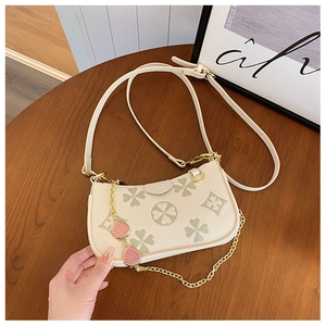 Detail of clover embossed cream shoulder bag with strawberry pendant and gold chain