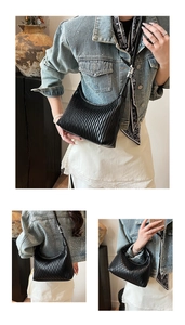 Detail of black pleated crescent bag featuring vertical texture and smooth faux leather