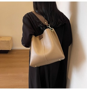 Close-up of khaki bucket bag showing the wide shoulder strap and soft leather texture
