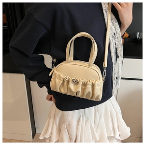 Detail of pleated cream crossbody bag featuring silver metallic twist lock and soft PU texture