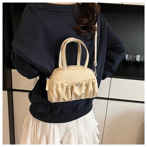 Detailed view of cream pleated crossbody bag with silver clasp and slim strap worn by model