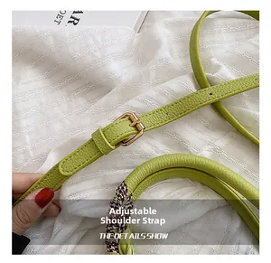 Detail view of adjustable green leather shoulder strap with gold buckle and houndstooth scarf