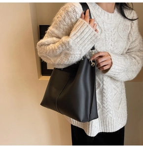 Close-up of black matte leather tote bag featuring gold hardware and vertical stitching