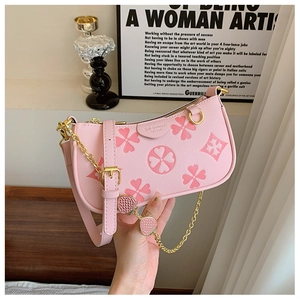 Detailed view of pink shoulder bag with clover pattern and strawberry charms