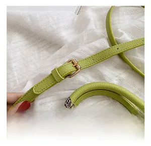 Close-up of lime green leather handbag with hardware buckle and houndstooth silk scarf detail