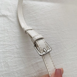 Detail of white crocodile embossed leather strap with adjustable silver metal buckle