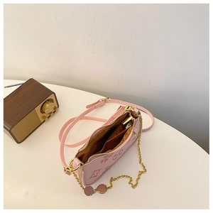 Detail view of pink crossbody bag with clover patterns and golden chain strap