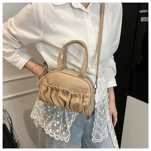 Close-up of pleated beige handbag featuring gold metal clasp and detachable shoulder strap