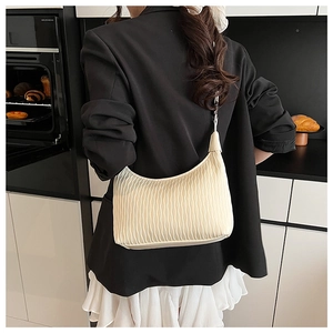 Chic off-white pleated shoulder bag shown on model in a modern kitchen background