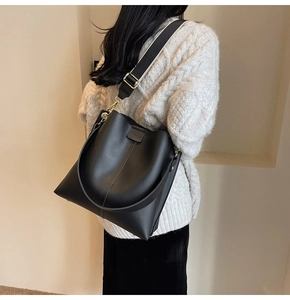 Detail of black large bucket tote bag with wide canvas strap and matte leather texture