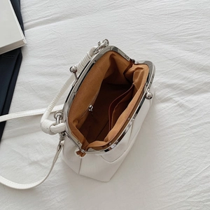 Top view of white leather kiss-lock bag showing brown fabric lining and inner pockets