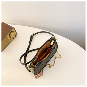 Close-up of black embossed leather handbag with internal pockets and strawberry charm
